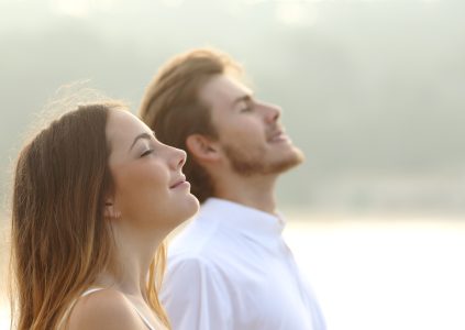 Profile of man and woman breathing deep fresh air together at sunset