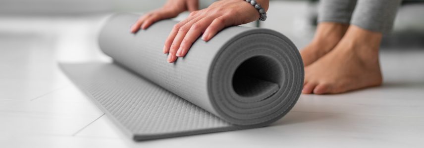 Rolling out a yoga mat on the floor