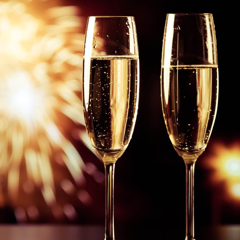 Fireworks going off at New Year and two champagne glasses in the foreground