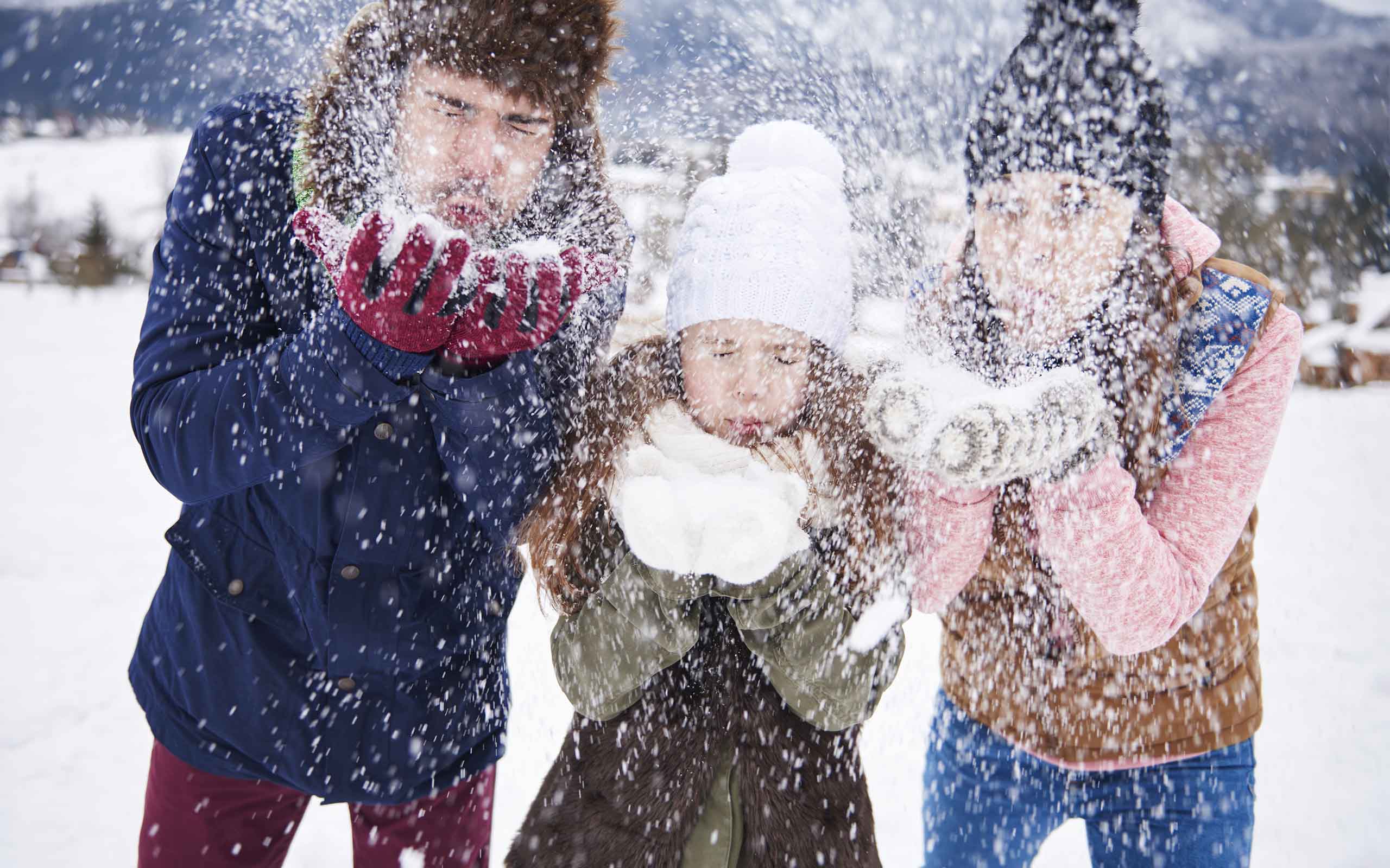 A family blowing snow out of their hands