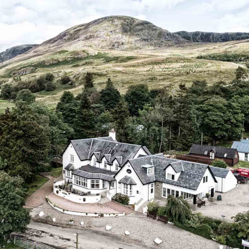 The exterior of Glen Clova Hotel with rolling Scottish hills in the background