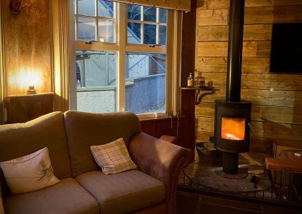 A sofa next to a lit log burner in The Bothy at Glen Clova Hotel and Lodges in Scotland