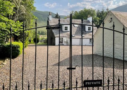 A view of The Old Manse exterior through its elegant wrought iron gates at Glen Clova Hotel and Lodges in Scotland