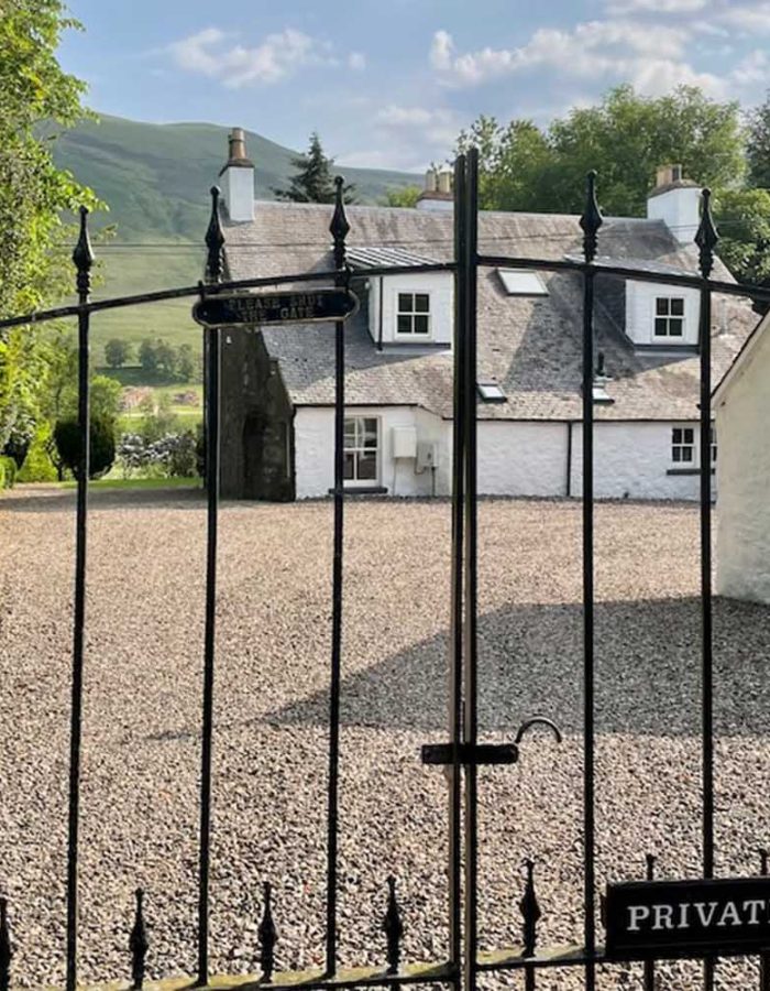 A view of The Old Manse exterior through its elegant wrought iron gates at Glen Clova Hotel and Lodges in Scotland