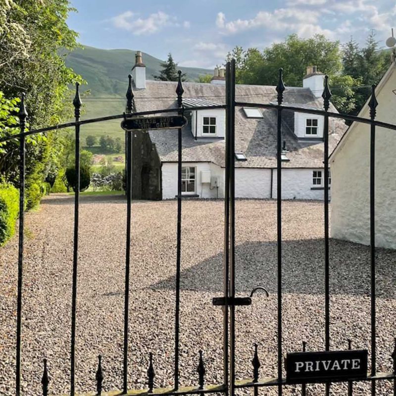 A view of The Old Manse exterior through its elegant wrought iron gates at Glen Clova Hotel and Lodges in Scotland