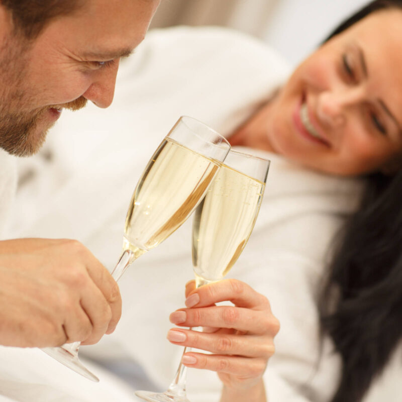 Couple in bathrobes enjoying a romantic break with glasses of champagne