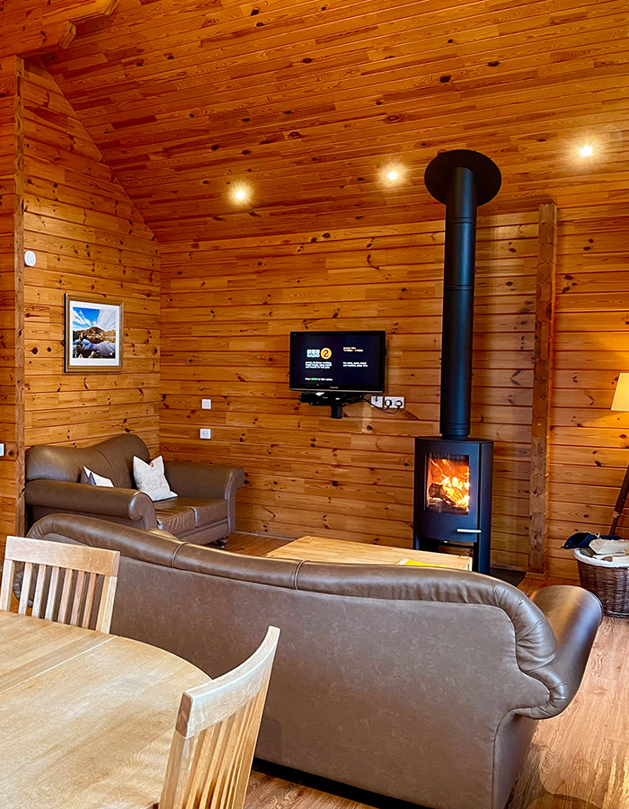 A living room with a stove in a Clova Lodge at Glen Clova Hotel