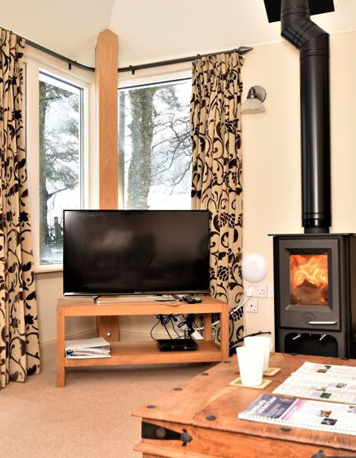 The living room with a wood burning stove in Brandy Cottage at Glen Clova Hotel