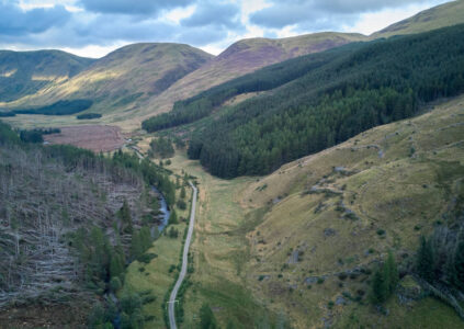 An aerial view of Glen Doll - mountains, pine forest on slopes and a road