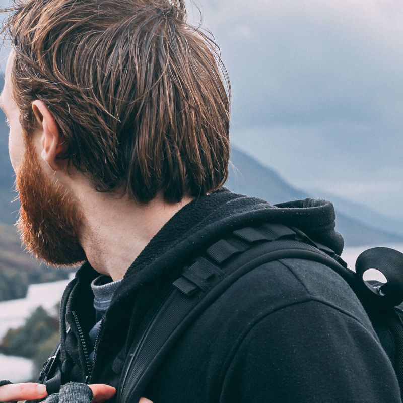 A male hiker looks out over the distant hills in the Scottish Highlands