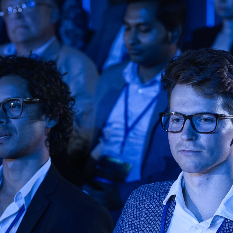 Audience lit in blue, at an industry event conference